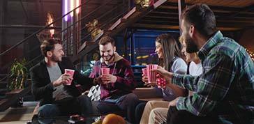 After a hard working day in a modern office studio young people workers came all together on the sofa to make a little stuff party they cheers with cups and enjoying the time