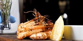 Final touch concept. Restaurant dish serving. Chef in gloves puts a small vase with rosemary and pepper on board with roasted tiger shrimps and sliced lime. Slow motion. hd