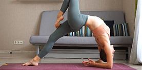Pretty girl is focused on yoga practice at home doing balancing exercises.
