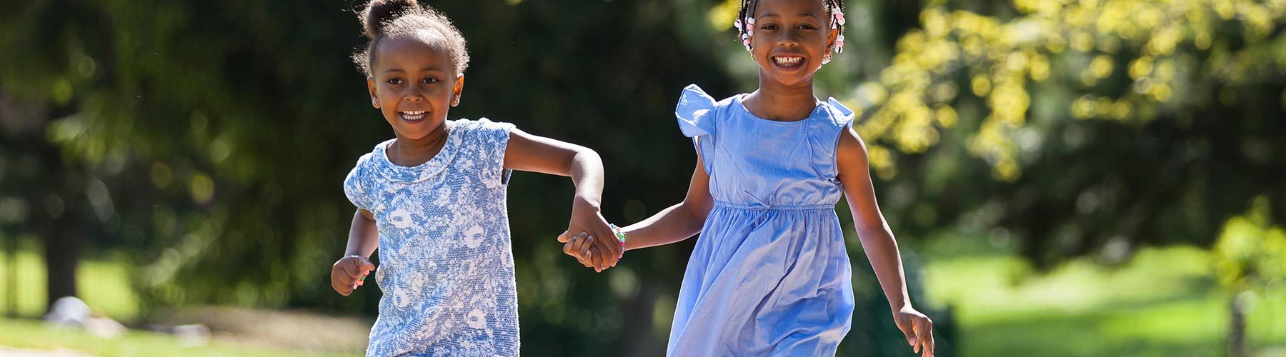 Outdoor portrait of a cute young black sisters running - Africa