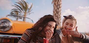 Young women on road trip eating candy and having fun